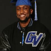 man with graduation cap and gvsu varsity jacket smiling for photo